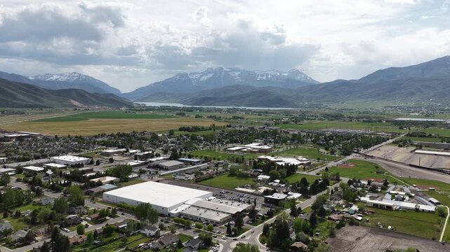 Aerial mountain town Heber City Utah in spring with snow capped mountains and dramatic sky