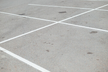 Fototapeta premium A large area of asphalt is shown with multiple empty parking spaces outlined by white lines. The scene captures the orderly arrangement and surfaces of the parking lot during daylight