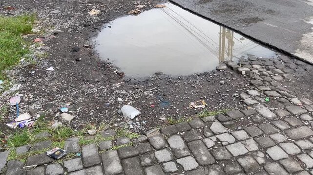 Pothole with muddy water puddle on broken asphalt road