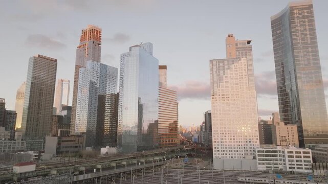 Long Island City skyline with modern glass skyscrapers and train yard at sunset in New York City.