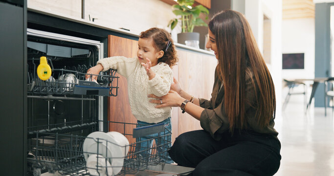 Child, helping and mother with dishes in kitchen for hygiene, teaching cleanliness and guidance. Smile, woman or toddler with dishwasher for sanitation, household chores and supervision for tidy home