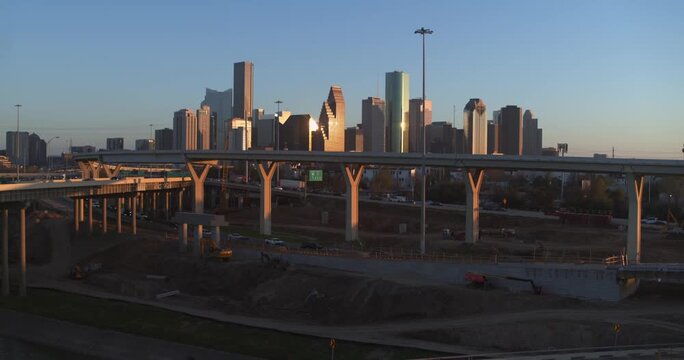 Drone footage of downtown Houston skyline at sunset with highway construction in foreground.
