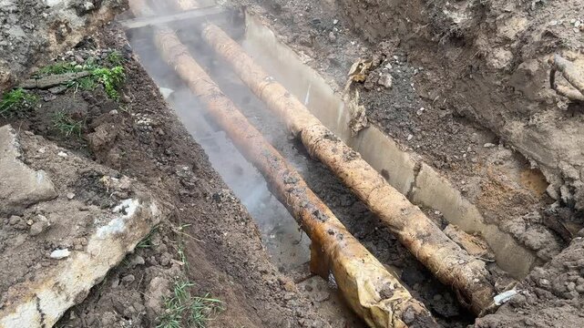 Utility workers repairing damaged district heating pipes in underground trench after infrastructure emergency accident