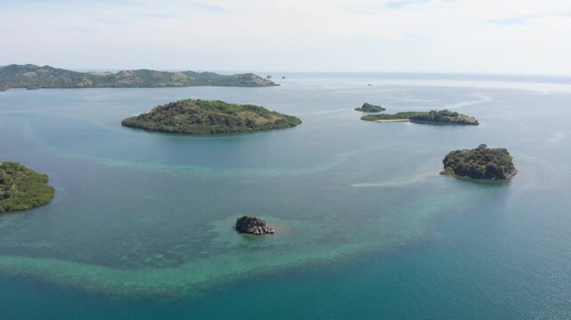 Panoramic aerial view of the 17 Islands Marine Park near Riung, Flores, Indonesia, featuring turquoise coral reefs, tropical islets, and deep blue ocean under a bright sky