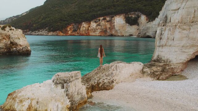 Woman with long hair explores hidden cove and emerald sea cliffs in Kefalonia Greece
