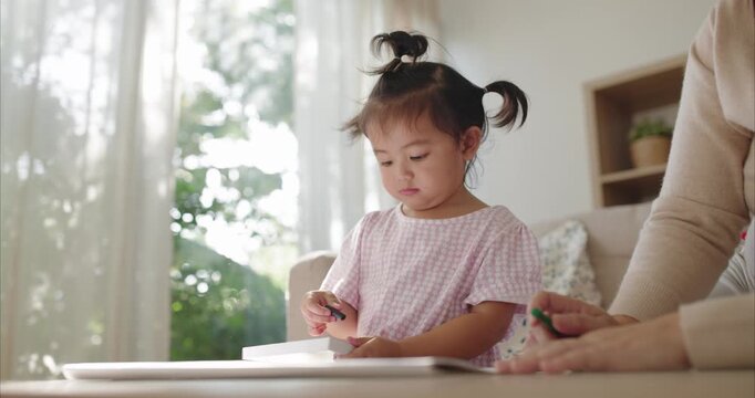 Asian Mother and Toddler Girl with Pigtails Drawing at Table; Happy Family Bonding, Learning Activity and Child Development in Cozy Bright Home Living Room