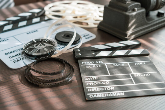 Movie clapper board and film strip on wooden table. Concept of filmmaking and cinematography.