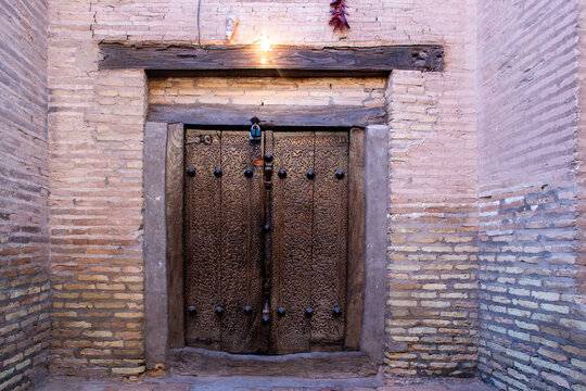 Traditional Uzbek carved wooden doors in Khiva, Uzbekistan. The doors are decorated with intricate floral and geometric patterns, crafted using traditional wood carving techniques.