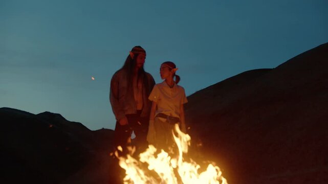 Stylish fantasy couple with elf ears posing together in a desert landscape. Cinematic lighting, flowing outfits, and surreal atmosphere create an epic fantasy-inspired fashion scene.