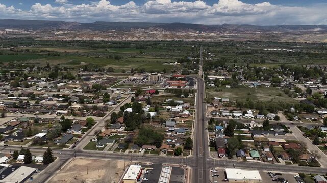 Aerial above small desert town Vernal Utah in spring with cloudy sky surrounding by hills