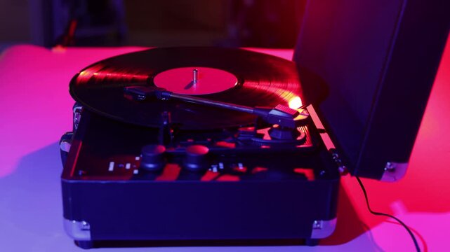Vintage record player with vinyl spinning under colorful neon lights