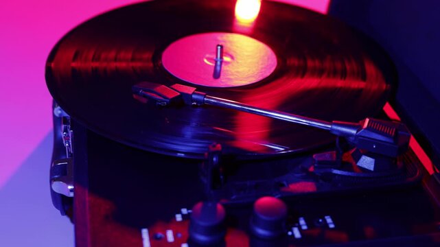 Close-up of a spinning vinyl record on a turntable with red and blue lighting