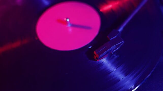 Close-up of a spinning vinyl record with vibrant neon lighting