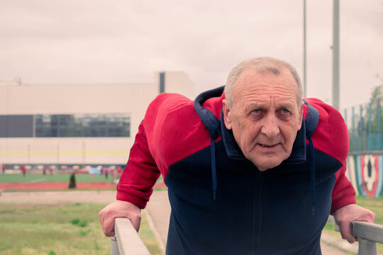 Senior man doing outdoor exercise on parallel bars at sports ground
