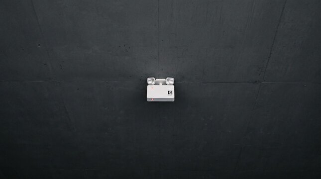 Emergency exit light fixture on dark industrial ceiling