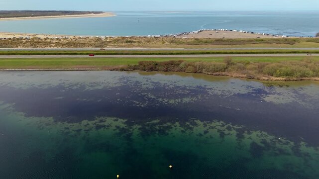 Aerial view of a mussel or oyster farm in the Dutch coastal waters. Industrial mariculture structures in a blue bay near sand dunes and the North Sea, showcasing sustainable seafood production.