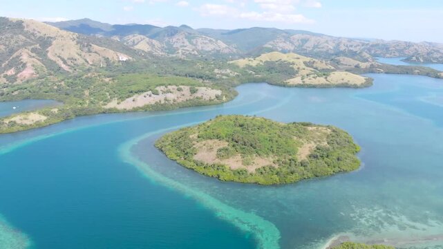 Panoramic aerial view of the 17 Islands Marine Park near Riung, Flores, Indonesia, featuring turquoise coral reefs, tropical islets, and deep blue ocean under a bright sky