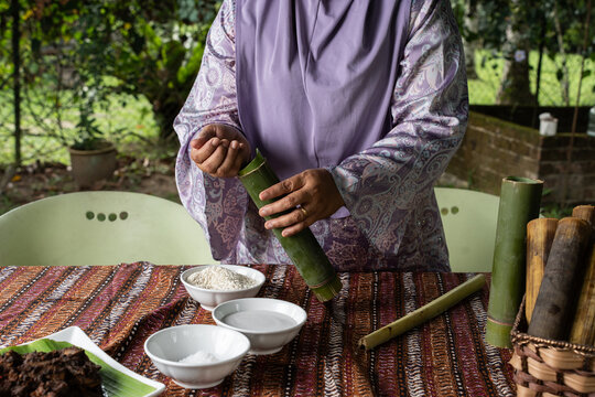 Woman Filling Bamboo With Rice For Traditional Lemang