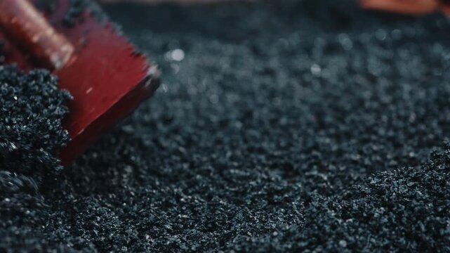 Spreading rubber crumb mixture with leveling tool close up