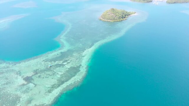 Panoramic aerial view of the 17 Islands Marine Park near Riung, Flores, Indonesia, featuring turquoise coral reefs, tropical islets, and deep blue ocean under a bright sky