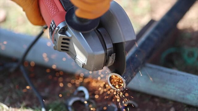 Man is cutting a metal list by angle grinder saw.