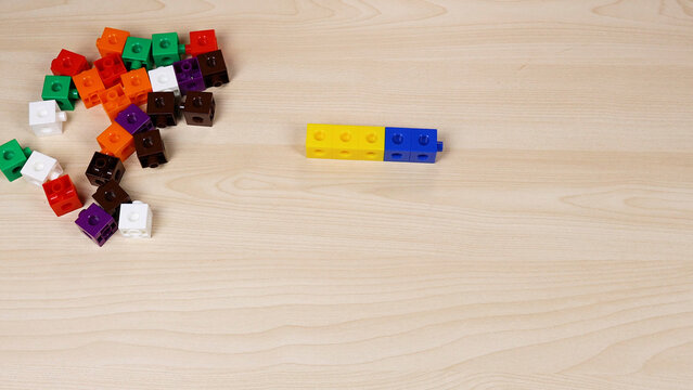 Colorful plastic interlocking cubes scattered on a light wooden table surface
