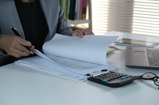 Young business woman working at desk. document check concept with a businessman open a document sheet and using pen to write and checking
