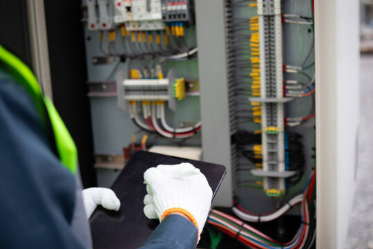 Gloved engineer documents wiring inspection inside an electrical control cabinet, supporting substation maintenance, safety diagnostics, and power grid reliability.