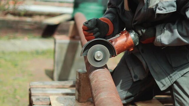 Homeowner repairs rusty metal pipe on backyard property using electric grinder and protective gloves. Flying sparks and outdoor setting reflect practical DIY maintenance and home improvement work.