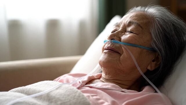 Senior Asian Woman Resting in Hospital Bed with Nasal Oxygen Cannula during Medical Treatment and Recovery