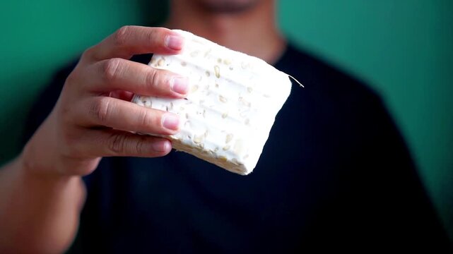 Holding tempe (fermented soybean). Tempe usually wrapped in banana leaves. Indonesian vegan food.