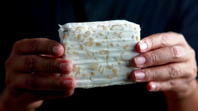 Holding tempe (fermented soybean). Tempe usually wrapped in banana leaves. Indonesian vegan food.