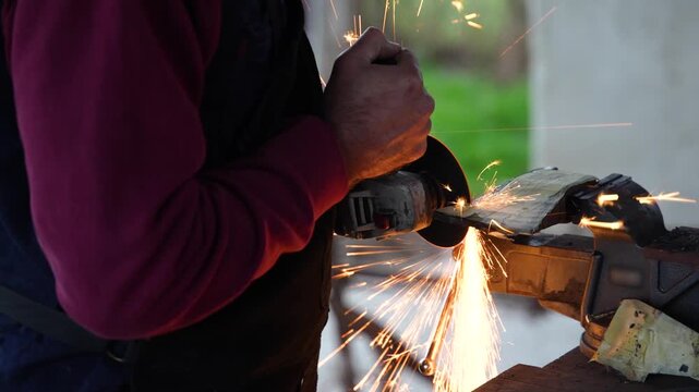 Close up of artisan sharpening metal with angle grinder in workshop