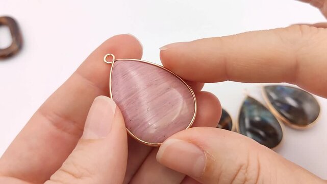 A close examination reveals the smooth finish and natural subtle patterns of a pink quartz cabochon pendant wrapped in a delicate gold frame for jewelry making projects