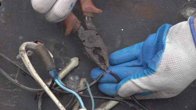 Electrician cutting wire with pliers close up, an electrician in gloves disconnects insulated wires with pliers