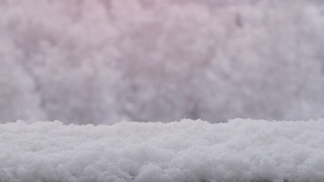 Sunny winter background copyspace with slow motion snow settling on railing with snow covered forest background, static shot.