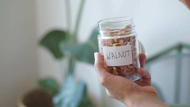 Hands holding a jar of walnuts in a kitchen