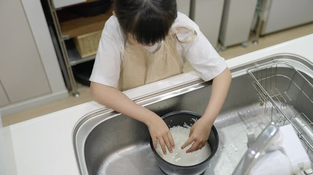 料理のお手伝いでお米を研ぐ子供