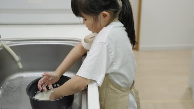 料理のお手伝いでお米を研ぐ子供