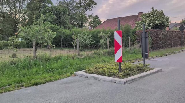 Flower bed in the road with a detour sign near a grassy area