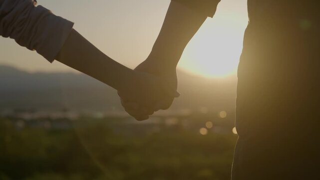 夕暮れのゴールデンアワーに手を繋ぐ母親と子供のシルエット、家族の絆
Silhouettes of a mother and child holding hands during a warm golden hour sunset