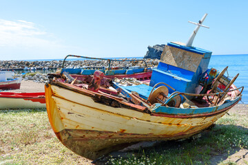 Obraz premium Colorful Weathered Fishing Boat on Coastal Beach in Skala Eresou, Greece