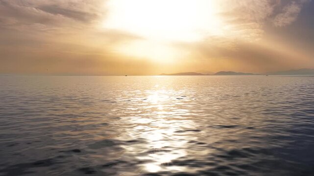Slow motion view of a golden sunset over calm sea with light reflections on the water as a background or texture