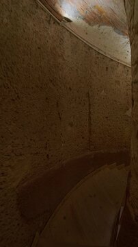 Vertical handheld footage of narrow underground corridor with rough stone walls and a curved passage leading into darkness. Catacombs of Kom El Shoqafa in Alexandria, Egypt