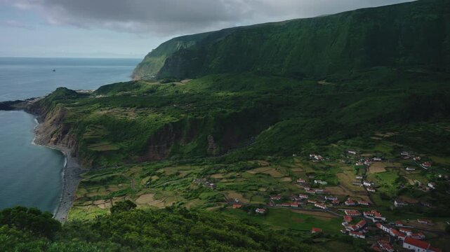 Cinematic Aerial View of Faj Grande Village Nestled Between High Green Cliffs and the Atlantic Ocean, Flores Island, Azores