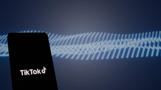 New Delhi, India - May 16 2026: TikTok logo on a smartphone with a blue abstract waveform background, short-form video app and digital entertainment concept