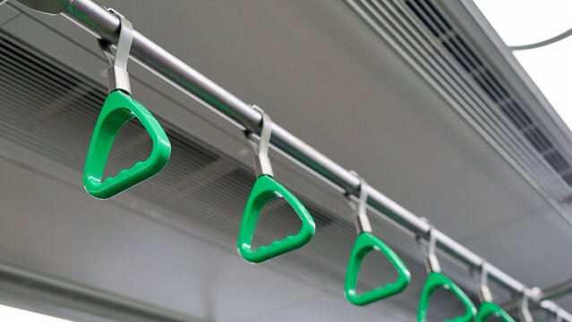 Row of green plastic hanging hand grips inside public transit