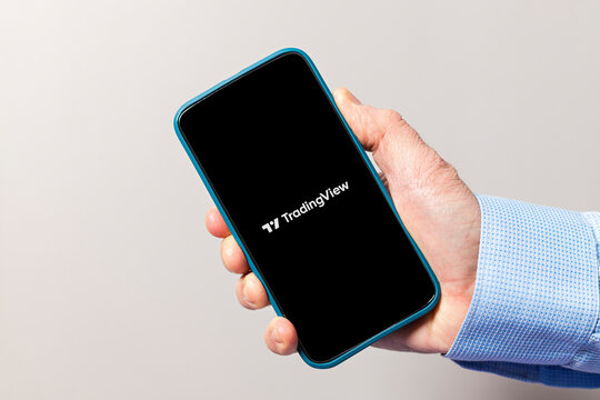 Hand holding smartphone displaying tradingview logo app