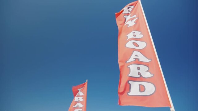 Flyboard and parasailing activity flags waving under clear blue sky on a sunny day.