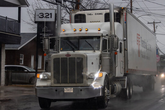 Canada, 13 April 2026 : Peterbilt semi-truck with Tremblay Express trailer and THE O KING branding drives on wet street